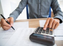 Close-up of male hands using calculator to examine report. Unrecognizable accountant counting profit. Businessman analyzing documents. Paperwork concept